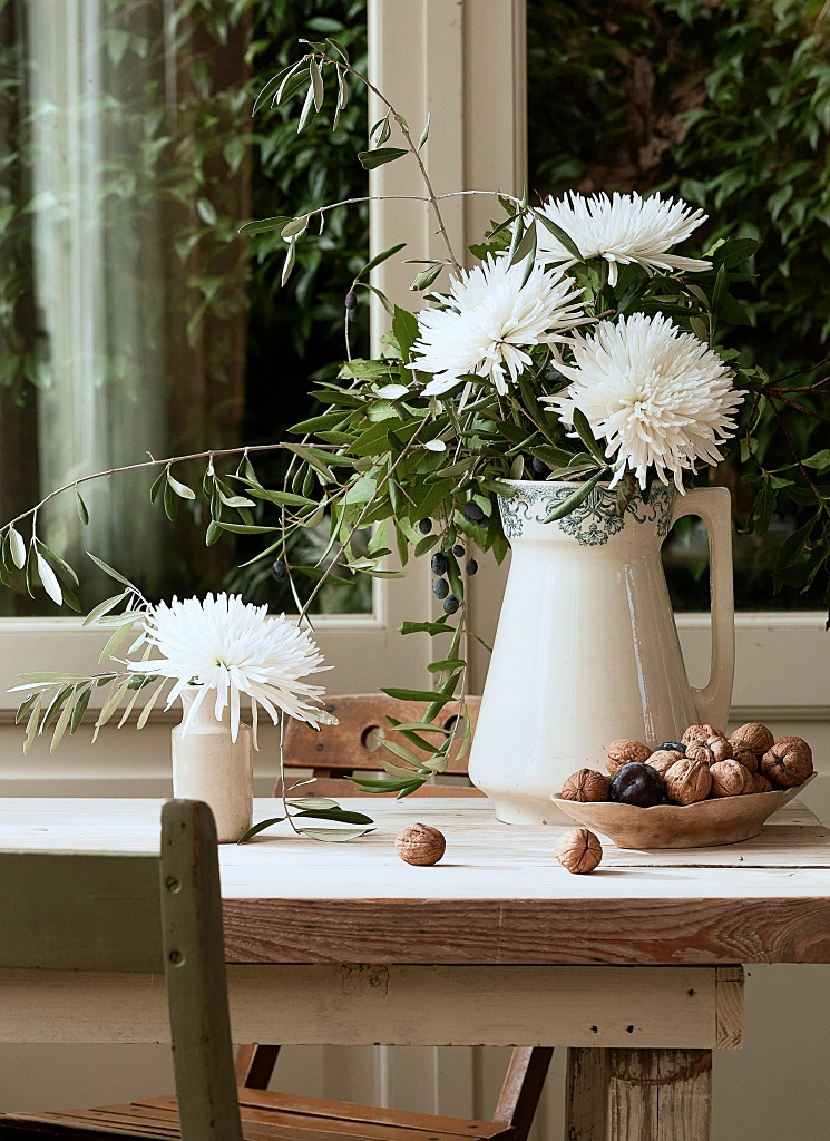 football mums in pitcher atop old wooden desk